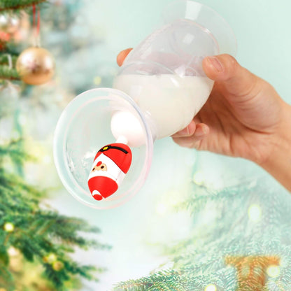 A hand holds a breast pump filled with milk, with a small Santa Claus figure stopper.