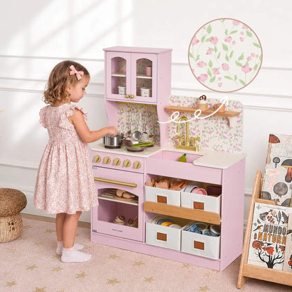 A young girl at Tiny Land® Wooden Play Kitchen - Pink, in a bright nursery setting.