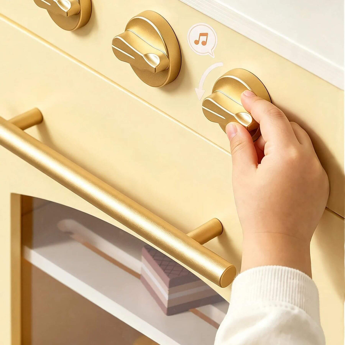 A close-up of a hand turning a gold control knob on a cream-colored toy or appliance