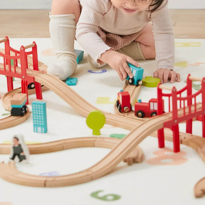 Child playing with a wooden train set on a carpeted floor