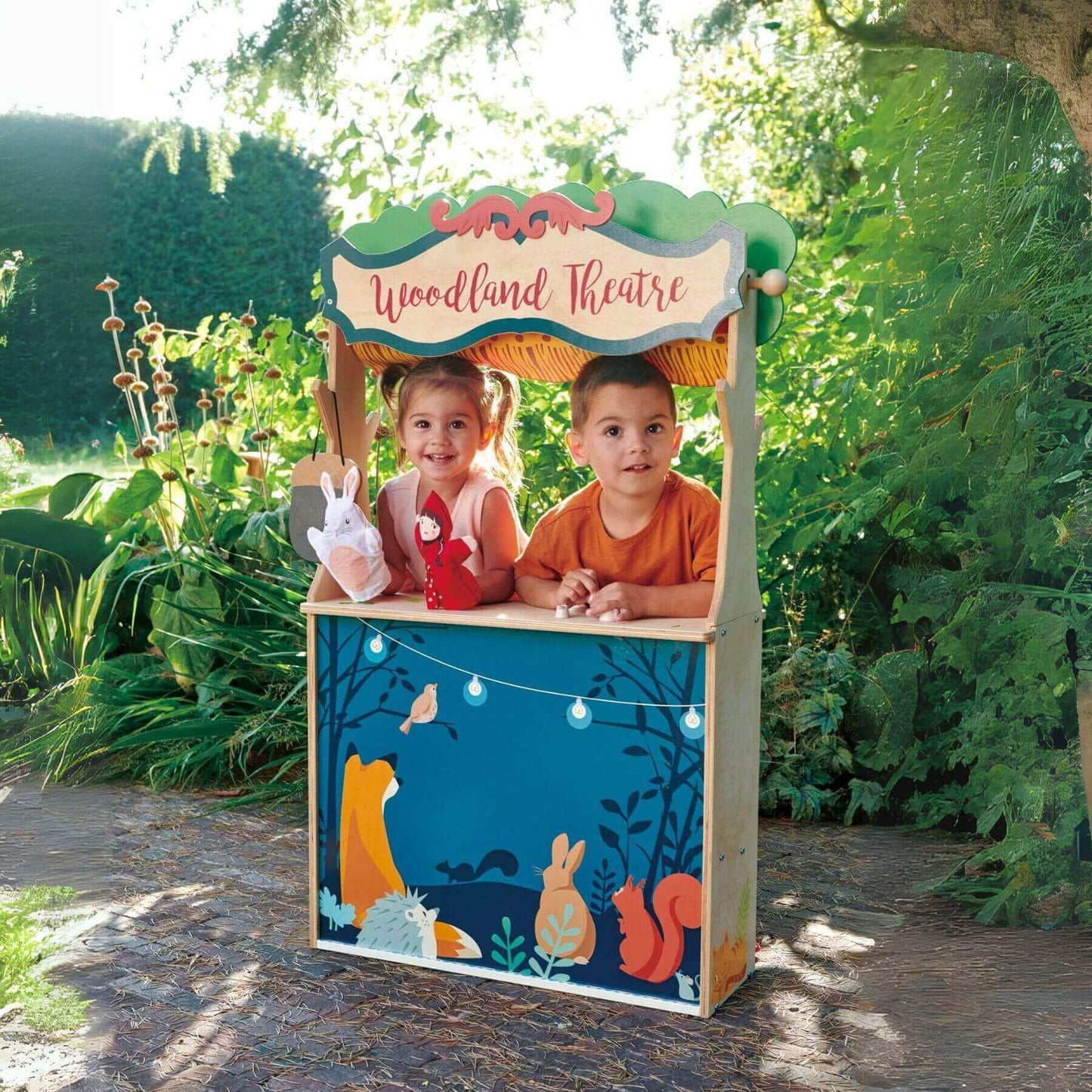Two children playing inside Tender Leaf Woodland Stores and Theater in a garden setting.