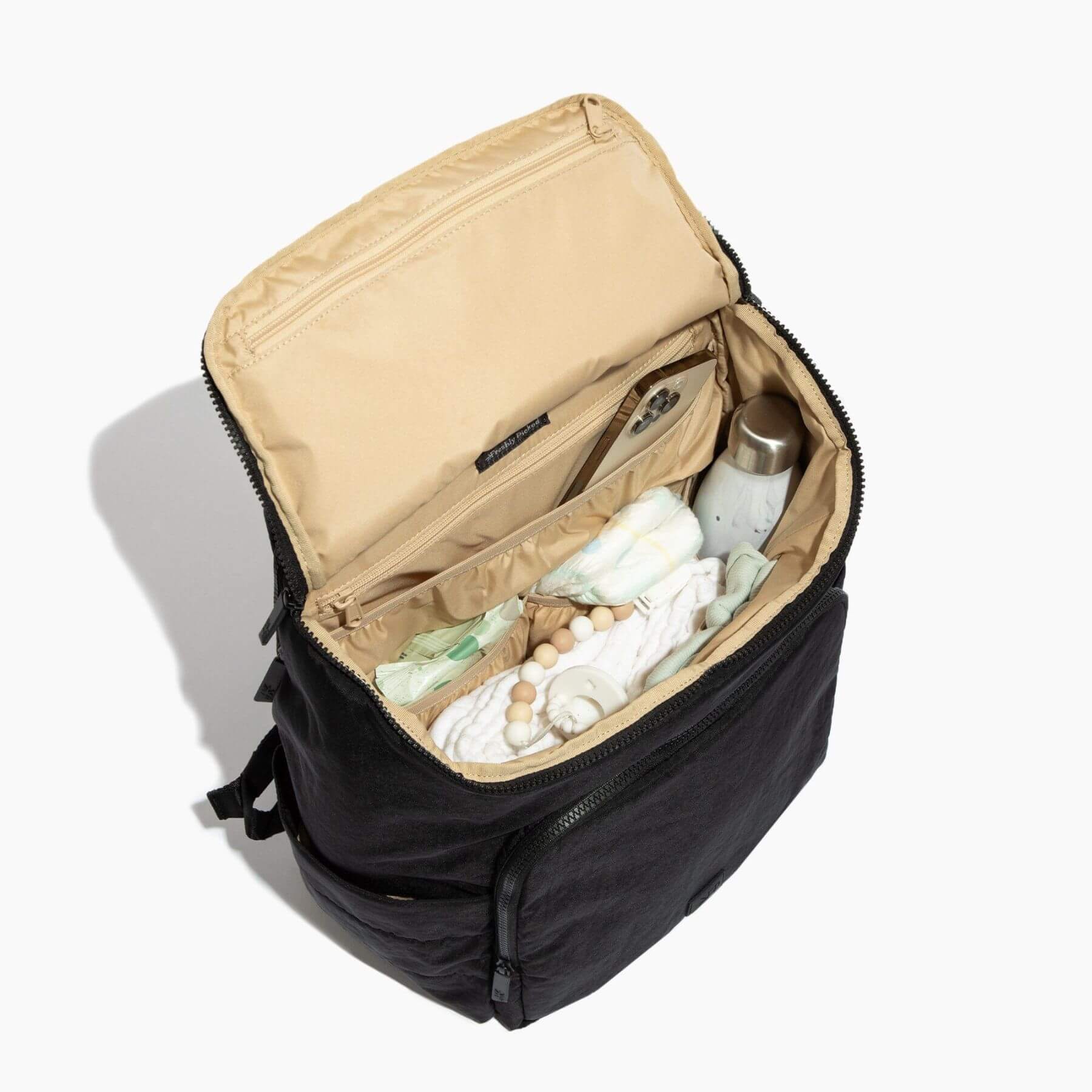 Black backpack with open compartment showing baby items on a white background